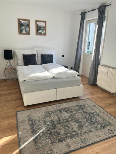 a white bed in a living room with a rug at Schöne Terassenwohnung in Böblingen