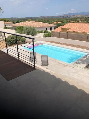 - une piscine avec une chaise à côté d'un bâtiment dans l'établissement Villa neuve avec piscine, à Bonifacio