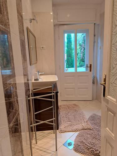 La salle de bains est pourvue d'un lavabo, d'un miroir et d'une porte. dans l'établissement Vintage Villa Magnolia, à Pula