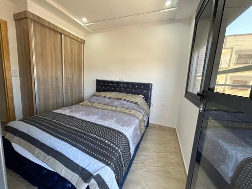 ein kleines Bett in einem kleinen Zimmer mit Fenster in der Unterkunft Appartement Relax Saidia in Saidia 