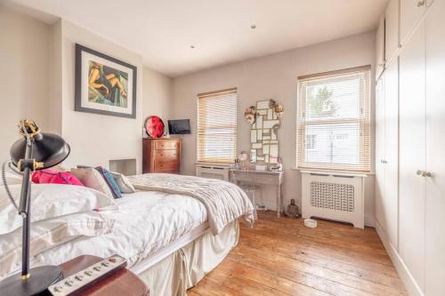 a bedroom with a bed and two windows at Stylish 2-Bed House With Office And Private Garden in Windsor
