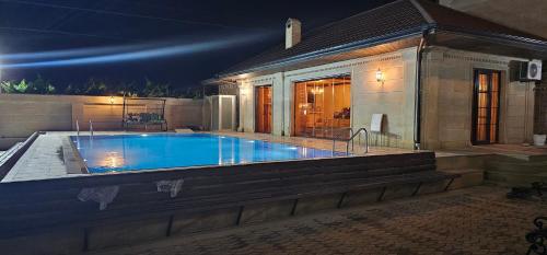a swimming pool in front of a house at night at Buzovna Villa in Baku
