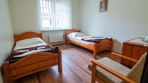 two beds in a small room with wooden floors at Dom Rekolekcyjny CEF Koszalin in Koszalin