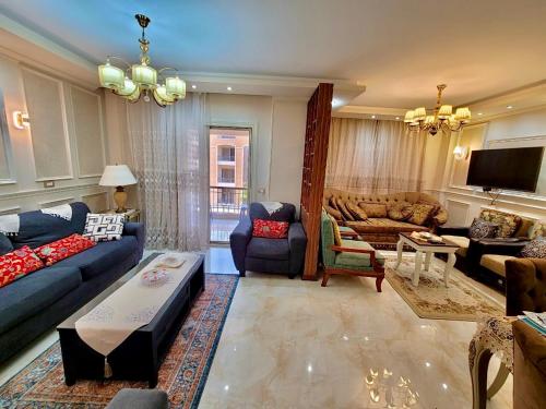 a living room with blue couches and a tv at Ultra Luxury 3BR with Pools ,Sports ,Dining in Gated compound, Close to all sites in Cairo