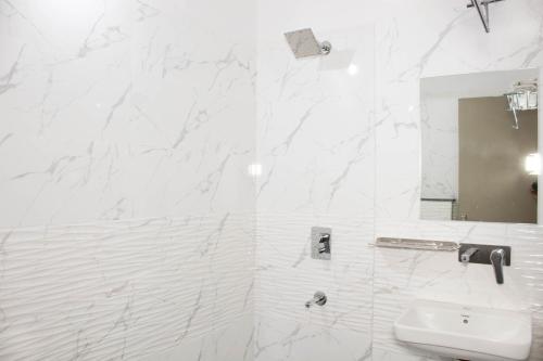 a white bathroom with a sink and a mirror at Hotel Kiwi Inn in Indore