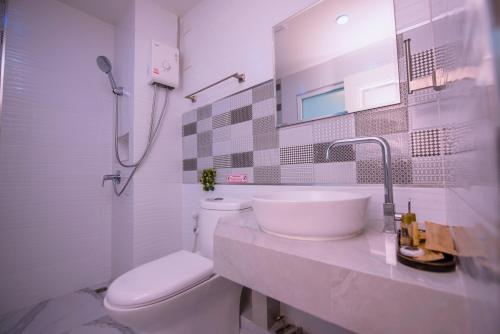 Baño blanco con lavabo y aseo en MS Hotel Sriracha en Si Racha