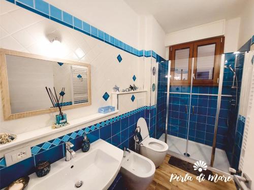 a blue tiled bathroom with a toilet and a sink at Appartamento Perla di Mare in Piombino