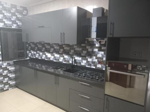 una cocina con electrodomésticos de acero inoxidable y armarios grises en 10mins to airport malls wifi no data en Accra