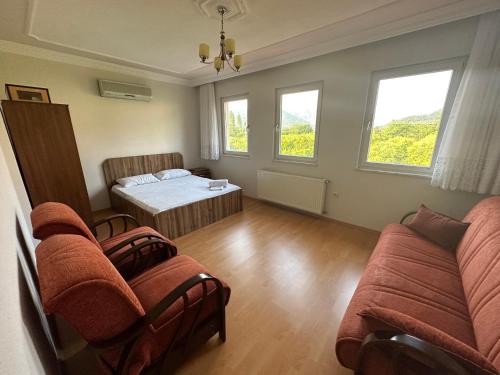 a room with a bed and a couch and windows at Aysel Villa in Ortaca