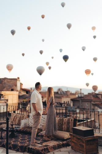 a man and woman standing next to a fence with kites at Zara Cave Hotel in Goreme