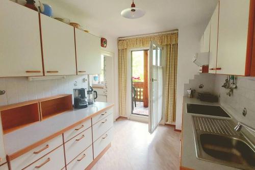 eine Küche mit weißen Schränken, einem Waschbecken und einer Tür in der Unterkunft Fallerhaus in Gmünd in Kärnten
