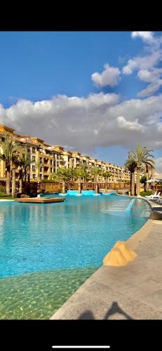 Una gran piscina de agua azul con edificios al fondo. en Ultra Luxury 3BR with Pools ,Sports ,Dining in Gated compound, Close to all sites, en El Cairo