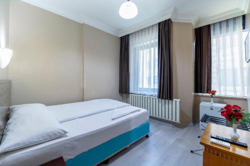 1 dormitorio con 1 cama, escritorio y ventanas en OTEL ÜMIT İSTANBUL en Estambul