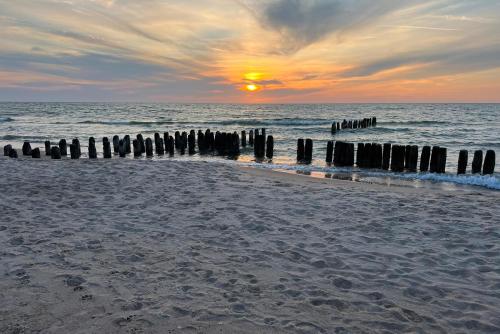 a sunset on a beach with a pier in the water at Seaside Escape Pet Friendly Apartments Mielenko by Renters in Mielenko