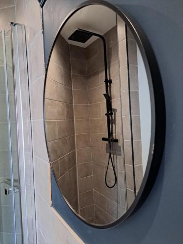 a round mirror with a shower in a bathroom at Manse Apartment in Great Malvern