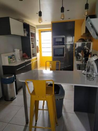 une cuisine avec une table et deux chaises jaunes dans l'établissement Jolie maison en pierres au calme dans un charmant village aux portes de Bayeux, à Carcagny