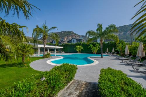 a swimming pool in a yard with chairs and umbrellas at Grand Gocek Hotel in Göcek