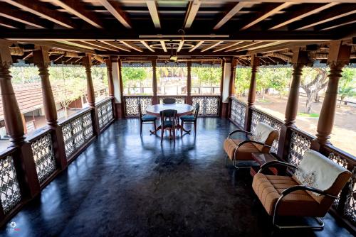 a porch with a table and chairs and windows at Meleppura Homestay in Chāvakkād