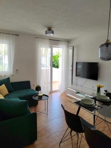 a living room with a green couch and a tv at Apartment Čiovo Radić in Trogir