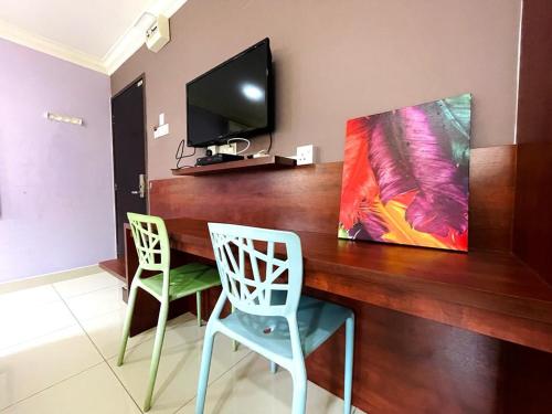 a wooden table with two chairs and a television on a wall at Hilltop Hotel Tanjung Malim in Tanjung Malim