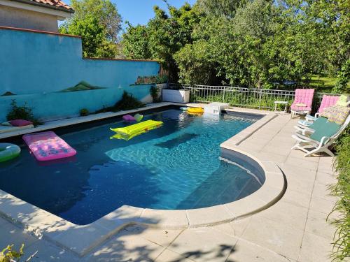 a swimming pool with two chairs and a pool noodle pool at Grand appartement indépendant, 4 personnes et plus, piscine et jardin in Toulouse