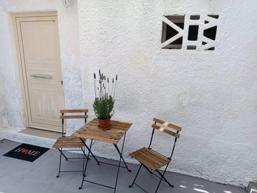 duas cadeiras e uma mesa com um vaso de planta ao lado de uma porta em Studio 'Katerina by the Sea' em Salamina