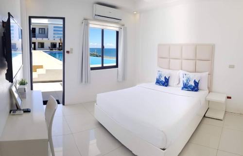 Dormitorio blanco con cama y vistas al océano en Blue Coast Beach Hotel, en Santa Ana
