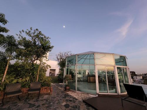 a glassconservatory with chairs and a table and trees at Bansabai Hostelling International in Bangkok