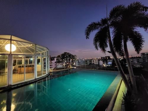 a swimming pool with a palm tree and a building at Bansabai Hostelling International in Bangkok
