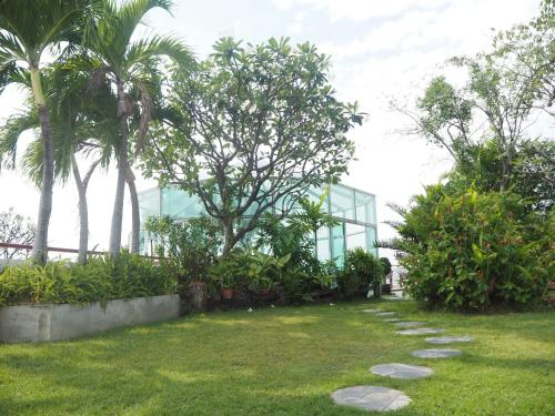 a garden with palm trees and a glass building at Bansabai Hostelling International in Bangkok