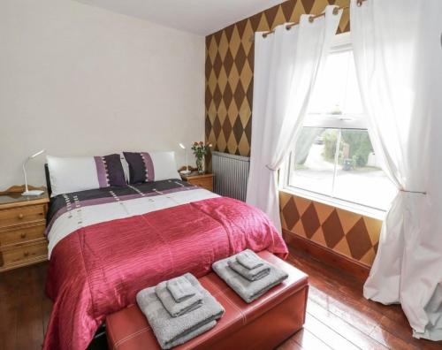 - une chambre avec un lit doté d'une couverture rouge et d'une fenêtre dans l'établissement Lovely Comfortable 3 Bed Home, Worcester, à Worcester