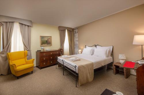 a bedroom with a bed and a yellow chair at Hotel Angelo d'Oro in Rovinj