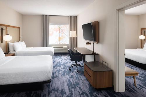 a hotel room with two beds and a desk and a television at Fairfield Inn & Suites by Marriott West Kelowna in West Kelowna