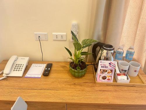 a wooden desk with a phone and a plant on it at MySpace Hotel Comembo Taguig in Manila