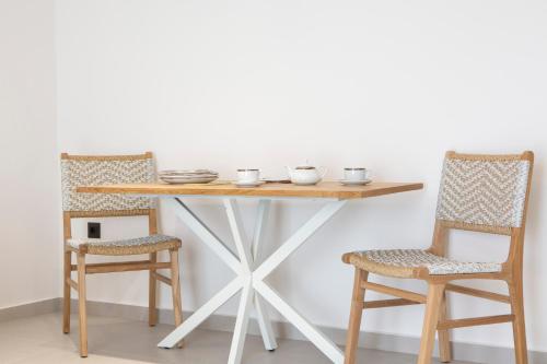 a wooden table with two chairs and a table with bowls on it at Achillion Suites in Lefkada Town