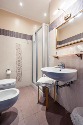 a bathroom with a sink and a toilet and a mirror at La Grotta Hotel in San Marino