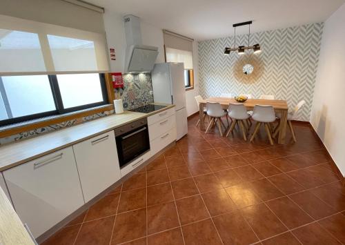 cocina con armarios blancos, mesa y sillas en House 9 Guimarães, en Guimarães