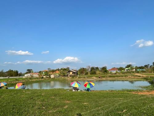 a group of people with umbrellas near a pond at KeawKangNa Farmstay แก้วก๋างนา ฟาร์มสเตย์ in Ban Chong (1)