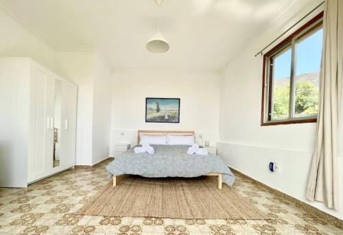 ein weißes Schlafzimmer mit einem Bett und einem Fenster in der Unterkunft Tenteniguada Enjoy Nature Villa in Las Palmas de Gran Canaria