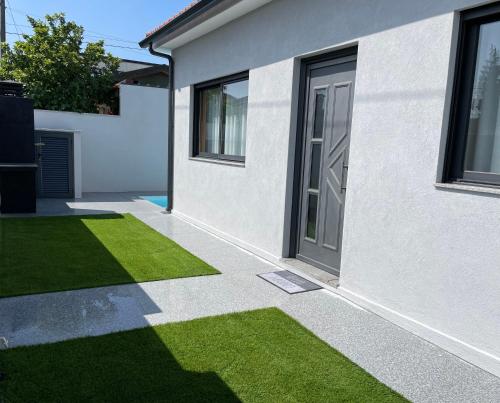 a white house with a yard of green grass at House 9 Guimarães in Guimarães