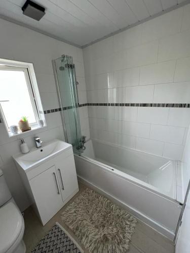 a bathroom with a tub and a toilet and a sink at Single room with Smart Tv in Luton