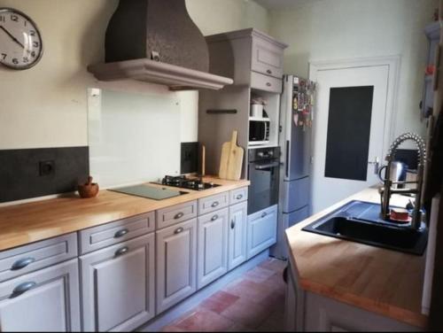 une cuisine avec des placards blancs et une horloge murale dans l'établissement Maison, Cité Plantagenêt, 20 m de la parade des pilotes 24 h, 20 mn en tram du circuit, au Mans