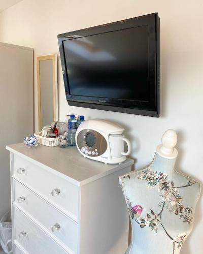 a flat screen tv on a wall with a dresser at Ardbrin Lodge in Dunadry