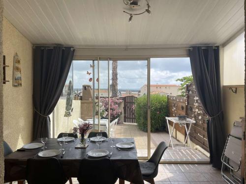 une salle à manger avec une table et une grande fenêtre dans l'établissement Maison cosy avec mezzanine, à 800m de la plage, 6 couchages, terrasse et parking privé - FR-1-229D-29, à Fleury