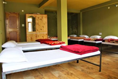 a room with four beds with red pillows on them at UpClimb Longstay for bus or taxi only guests in Manāli