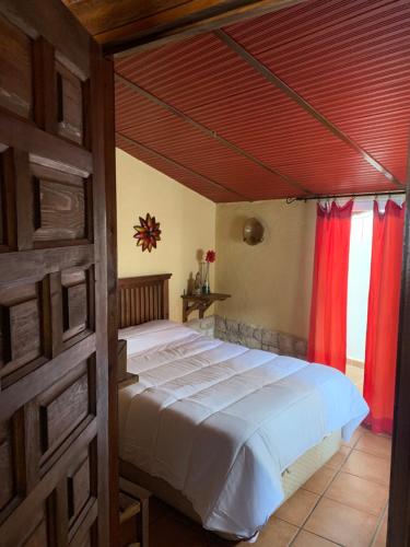 Schlafzimmer mit einem großen Bett und roten Vorhängen in der Unterkunft Casa Rural El Gran Encanto in Cazorla