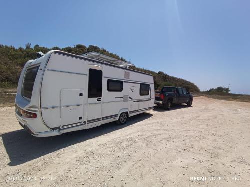 a white camper and a truck parked on a dirt road at Achziv Beach אכזיב חף in Liman