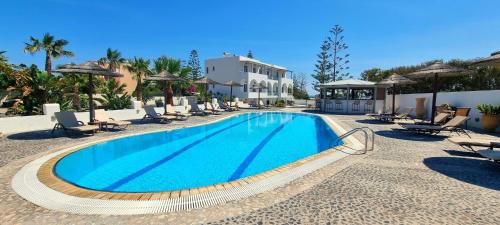 uma piscina num resort com cadeiras e um edifício em Horizon Resort em Kamari