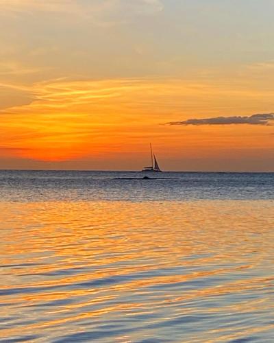 a sail boat in the ocean at sunset at Just Chill Villa in Trou aux Biches