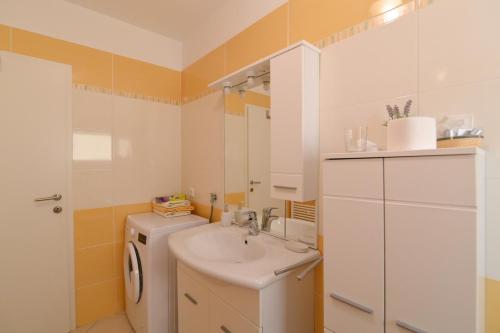 uma casa de banho com um lavatório e uma máquina de lavar roupa em Apartments Grozic Opatija em Opatija